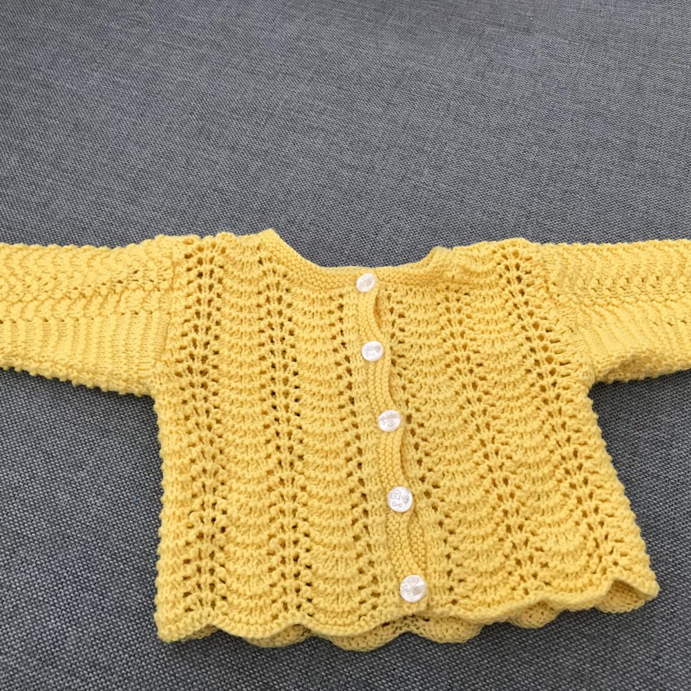 gul stickad tröja med knappar i mitten för att knäppa av/på. passar bebisar 0-3 månader