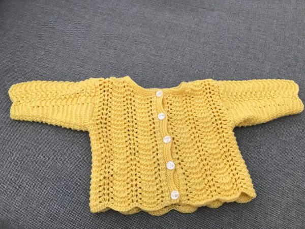 gul stickad tröja med knappar i mitten för att knäppa av/på. passar bebisar 0-3 månader